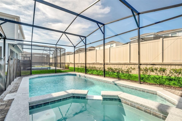 view of swimming pool featuring an in ground hot tub and a lanai