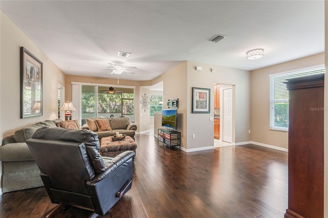 living area featuring dark wood-style floors, visible vents, and a wealth of natural light