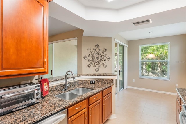 kitchen with dark stone countertops, a sink, visible vents, and brown cabinets