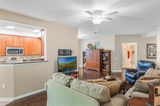 living area featuring ceiling fan, dark wood-style flooring, and baseboards