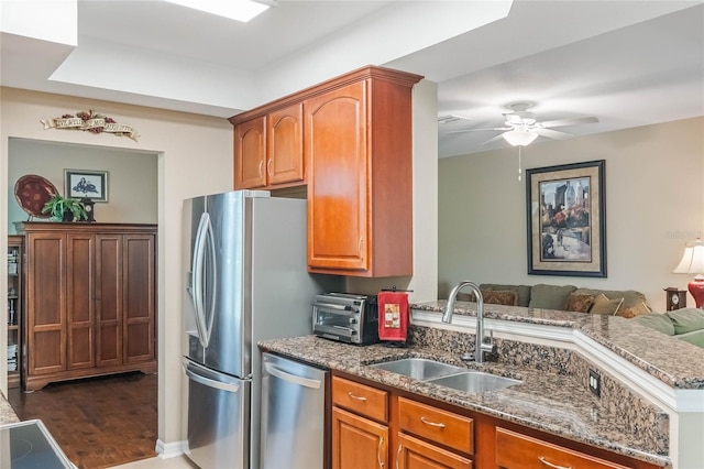 kitchen featuring a toaster, open floor plan, stainless steel appliances, stone counters, and a sink