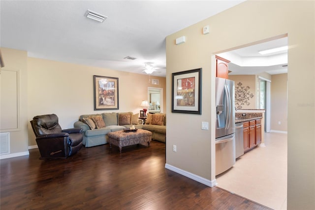 living area featuring visible vents, light wood-style flooring, and baseboards