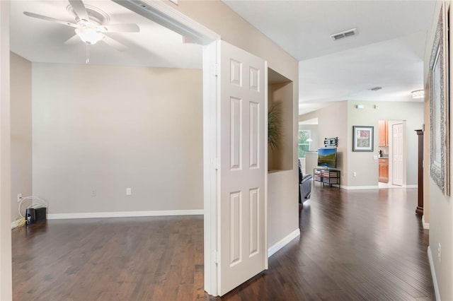 hallway with dark wood-type flooring, visible vents, and baseboards