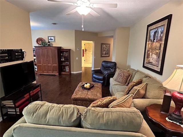 living area with visible vents, dark wood-type flooring, a ceiling fan, and baseboards