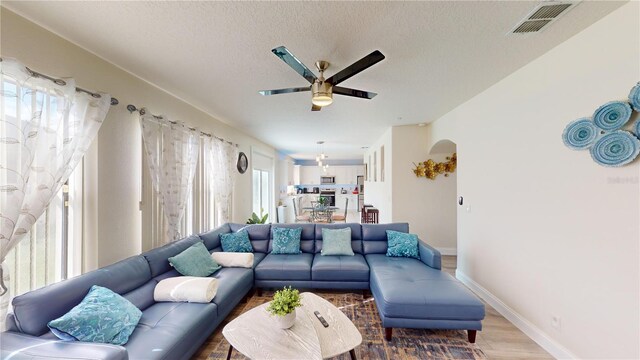 living room with hardwood / wood-style floors, ceiling fan, a textured ceiling, and a wealth of natural light