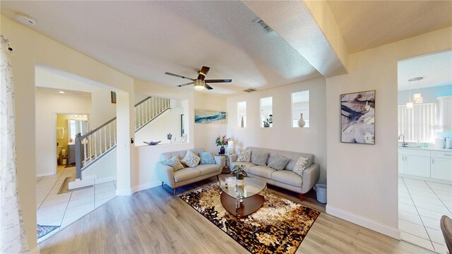 living room with ceiling fan, light hardwood / wood-style flooring, and a textured ceiling