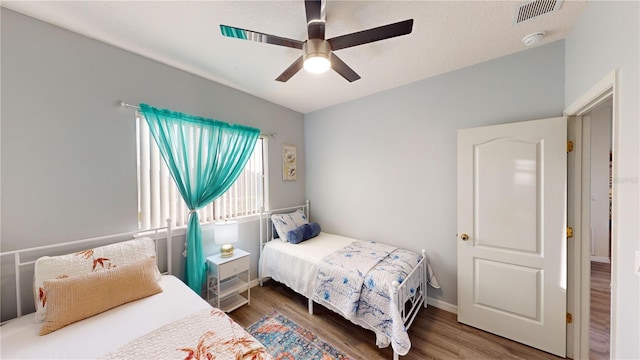 bedroom featuring ceiling fan, dark hardwood / wood-style flooring, and a textured ceiling