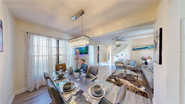 dining space with ceiling fan with notable chandelier and wood-type flooring