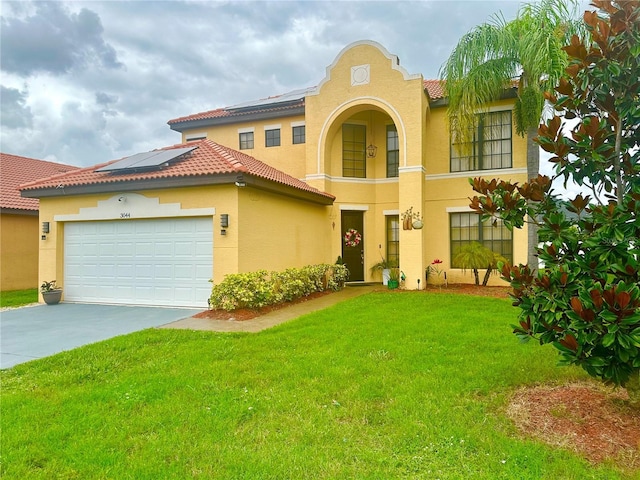 mediterranean / spanish-style house featuring driveway, stucco siding, a front lawn, a tiled roof, and roof mounted solar panels