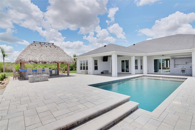 view of swimming pool featuring an outdoor kitchen, ceiling fan, a gazebo, a patio, and an outdoor bar