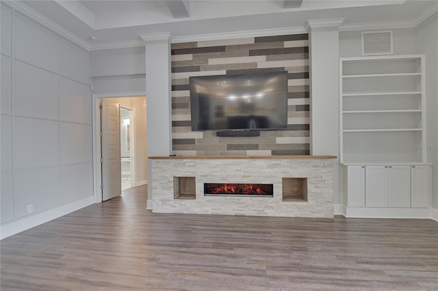 unfurnished living room featuring built in features, a stone fireplace, wood-type flooring, and crown molding