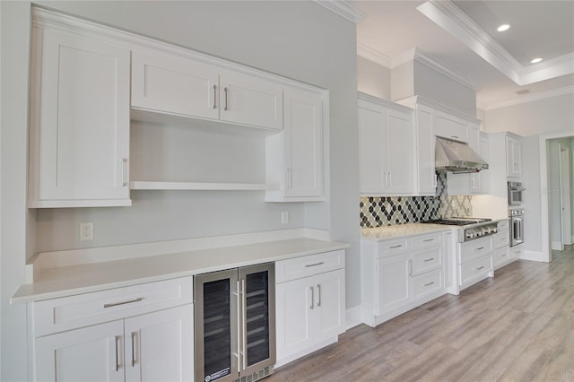 kitchen with beverage cooler, stainless steel gas cooktop, crown molding, decorative backsplash, and white cabinets