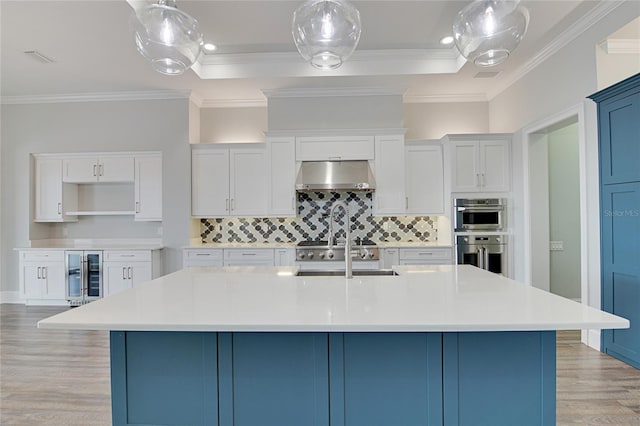 kitchen with a large island, sink, stainless steel double oven, and ventilation hood