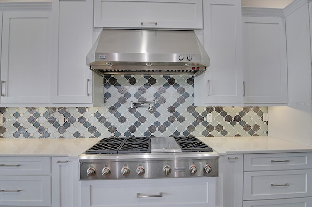 kitchen featuring white cabinets, wall chimney range hood, tasteful backsplash, light stone counters, and stainless steel gas cooktop