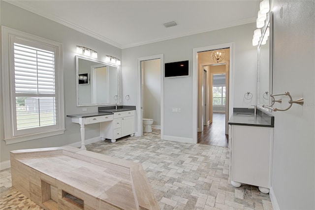 bathroom with toilet, vanity, and ornamental molding