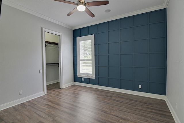 unfurnished bedroom with ceiling fan, a spacious closet, dark wood-type flooring, a closet, and ornamental molding