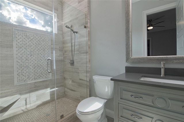 bathroom with an enclosed shower, vanity, toilet, and ceiling fan