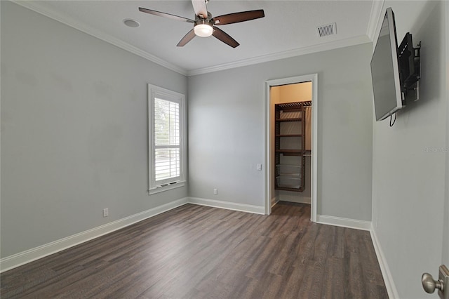 unfurnished bedroom featuring a walk in closet, ceiling fan, dark hardwood / wood-style floors, and ornamental molding