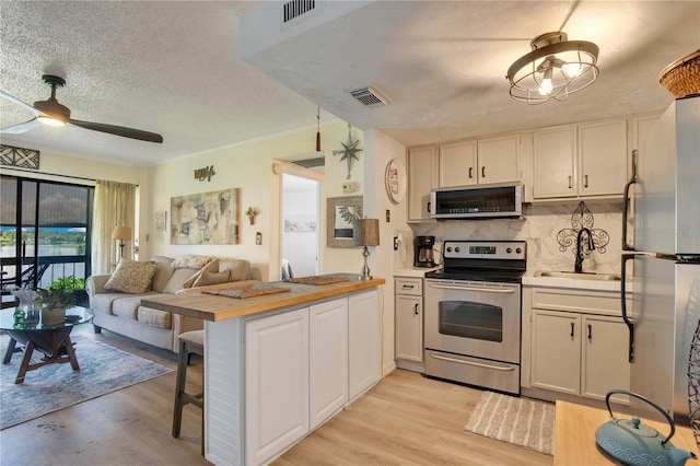 kitchen featuring stainless steel appliances, sink, white cabinets, and kitchen peninsula