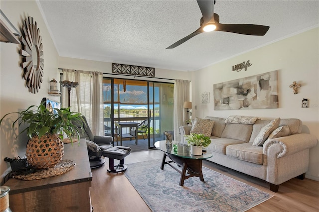 living room featuring hardwood / wood-style floors, ornamental molding, a textured ceiling, and ceiling fan