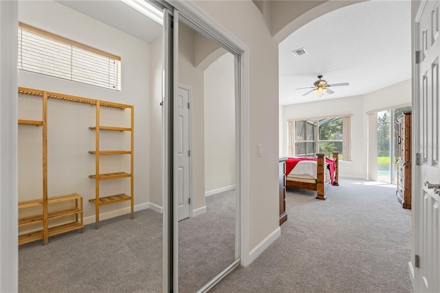 hall featuring arched walkways, light carpet, visible vents, and baseboards