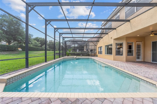 pool with glass enclosure, a yard, a ceiling fan, and a patio