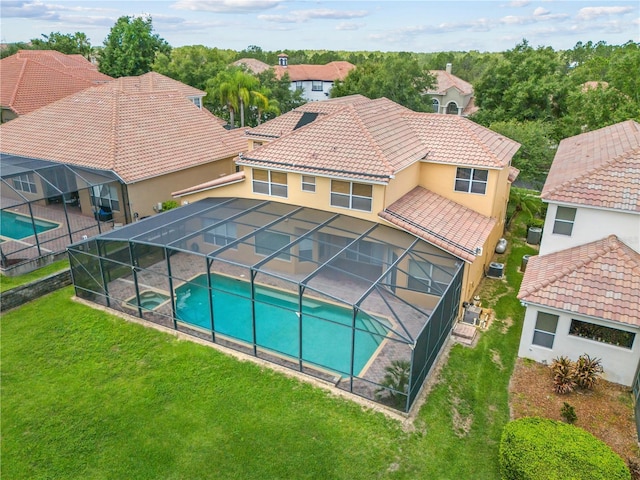 view of swimming pool featuring a pool with connected hot tub, a lanai, a lawn, and a patio