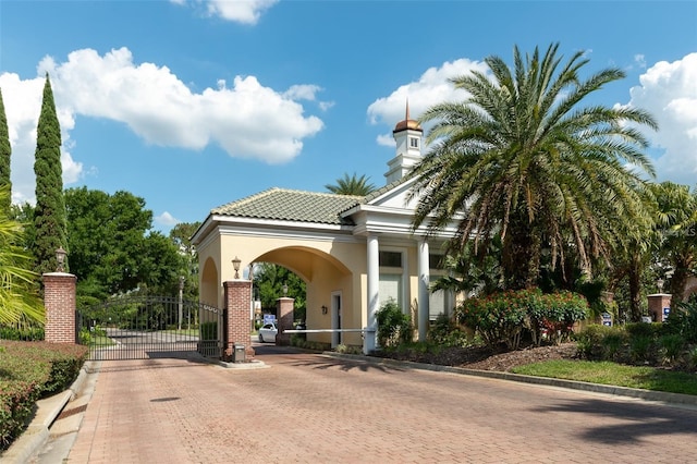 view of front facade featuring a tile roof, a gate, and stucco siding