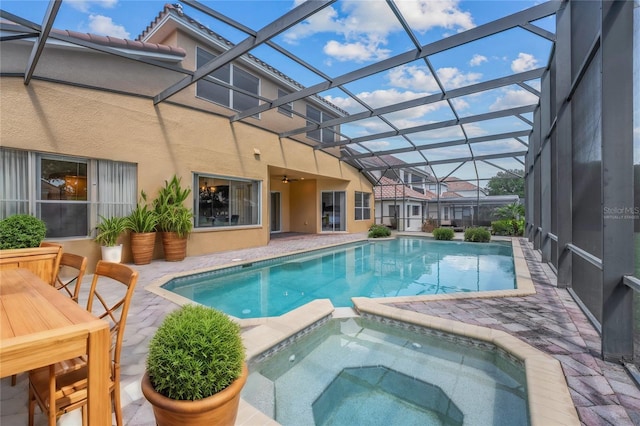 view of swimming pool with glass enclosure, an in ground hot tub, and a patio