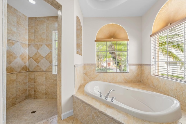 full bath with a wealth of natural light, tile patterned flooring, a garden tub, and a tile shower