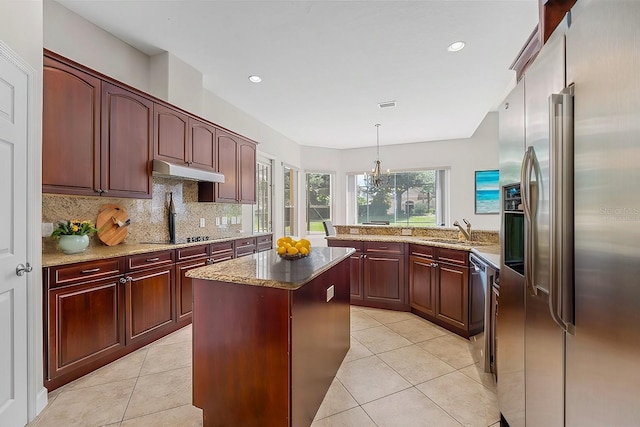 kitchen with a kitchen island, decorative light fixtures, stainless steel appliances, under cabinet range hood, and a sink