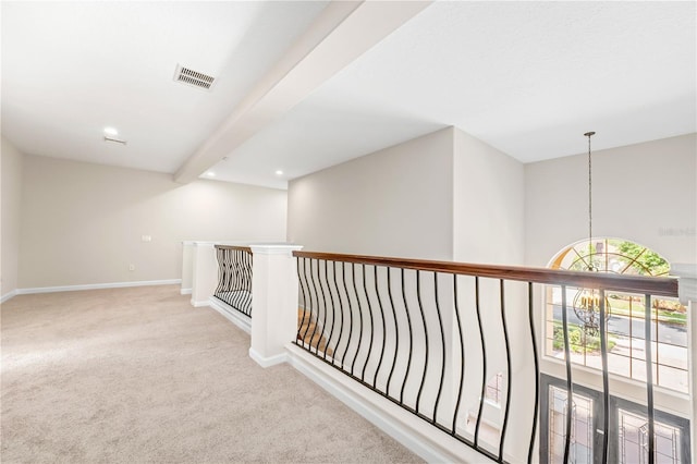 hallway featuring beam ceiling, light colored carpet, visible vents, a chandelier, and baseboards