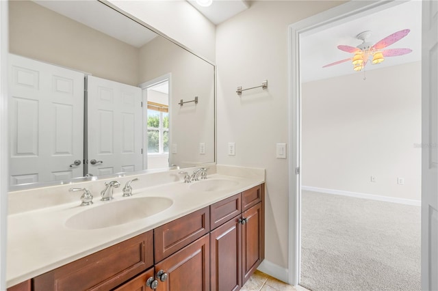 bathroom featuring ceiling fan, a sink, baseboards, and double vanity