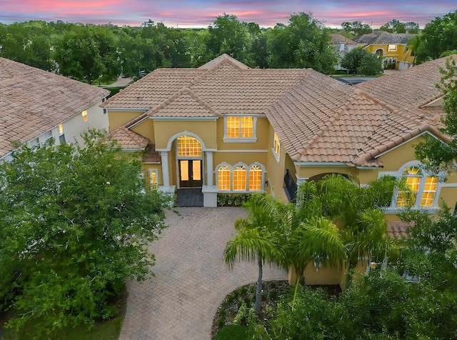 mediterranean / spanish home with stucco siding, decorative driveway, and a tiled roof