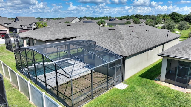 rear view of house featuring glass enclosure, a patio area, a fenced in pool, and a yard