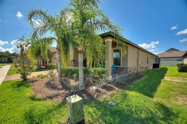 view of side of home with a yard and central AC