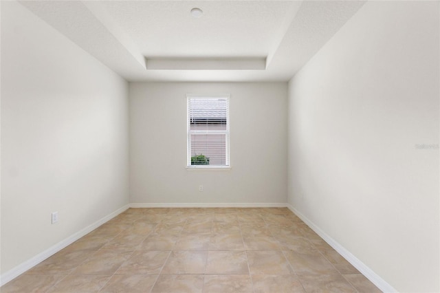 spare room featuring light tile patterned floors, a textured ceiling, and a raised ceiling