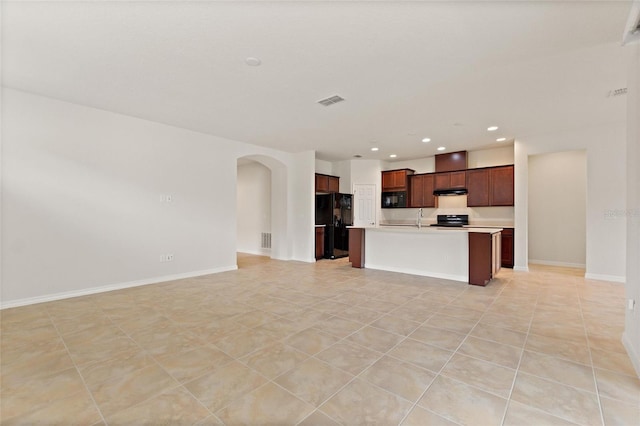 kitchen featuring black appliances, light tile patterned flooring, sink, and a kitchen island with sink