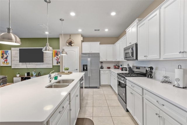 kitchen featuring pendant lighting, a center island with sink, light tile patterned floors, white cabinets, and appliances with stainless steel finishes