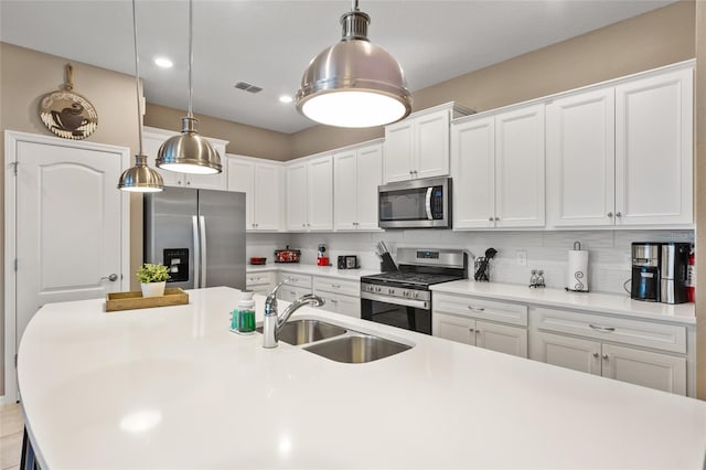 kitchen featuring stainless steel appliances, white cabinetry, sink, and pendant lighting