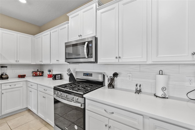 kitchen with stainless steel appliances, light tile patterned flooring, decorative backsplash, and white cabinetry