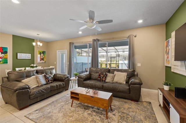 tiled living room featuring a textured ceiling and ceiling fan with notable chandelier