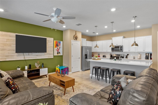 tiled living room with ceiling fan, a textured ceiling, and sink