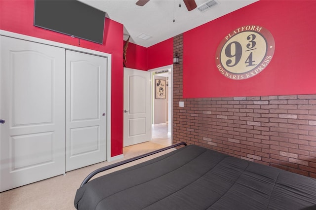 bedroom with ceiling fan, a closet, and brick wall