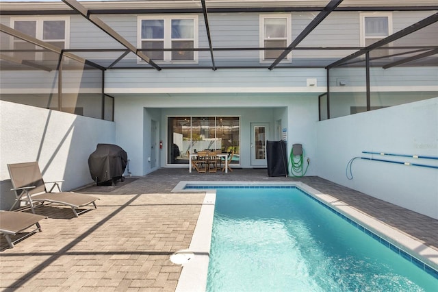 view of pool with a patio area, area for grilling, and glass enclosure