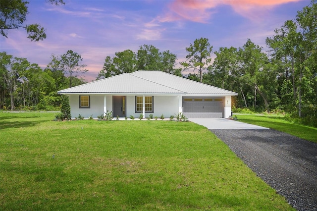 view of front of home featuring a yard, metal roof, driveway, and a garage