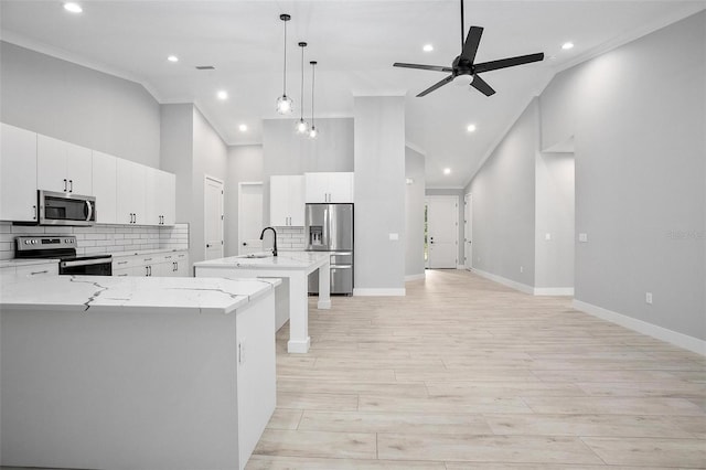 kitchen featuring stainless steel appliances, ornamental molding, a kitchen island with sink, high vaulted ceiling, and light wood-type flooring