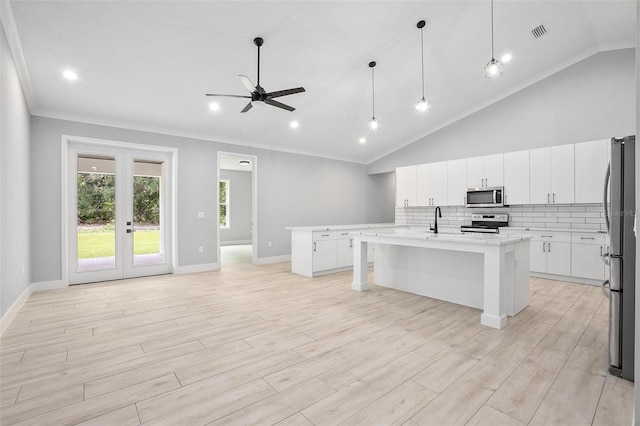 kitchen with stainless steel appliances, french doors, light wood-type flooring, backsplash, and an island with sink