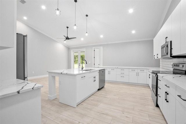 kitchen featuring light stone counters, appliances with stainless steel finishes, white cabinetry, a sink, and ceiling fan