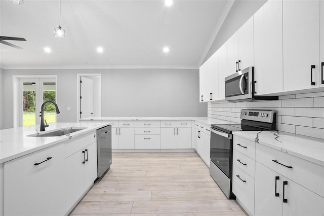 kitchen featuring stainless steel appliances, a sink, white cabinetry, light stone countertops, and tasteful backsplash